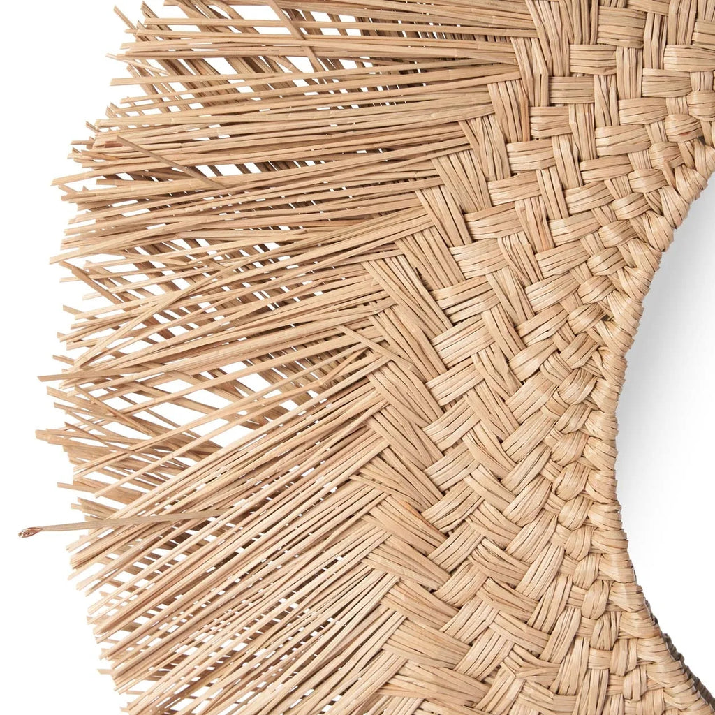 Detail van een ronde rotan spiegel met gevlochten rand en uitstekende vezels tegen een witte achtergrond.