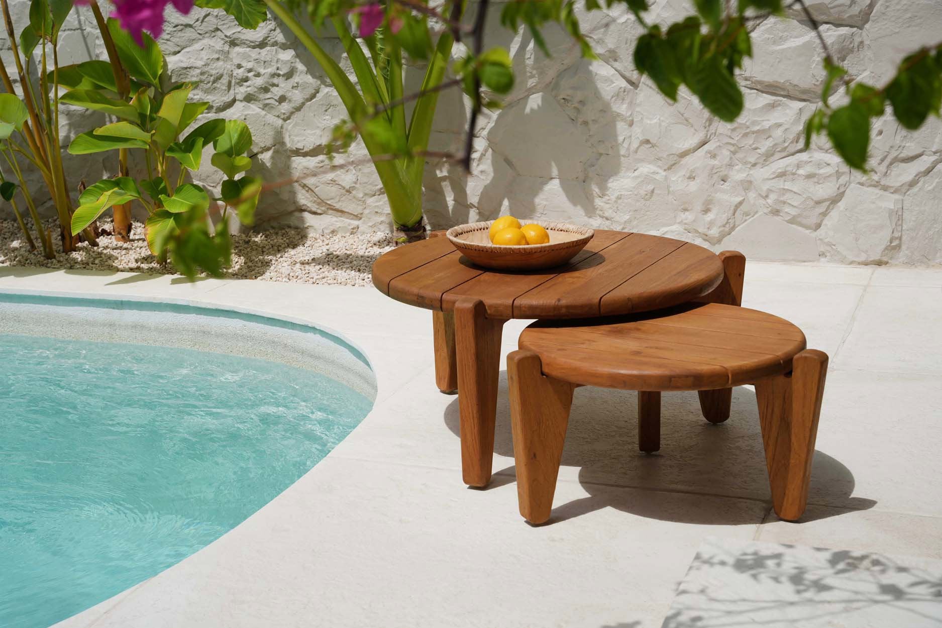 Speels duo van Seseh salontafels in naturel gerecycled teak van Bazar Bizar bij zwembad, elegant gestyled met rotan schaal boordevol gele citroenen