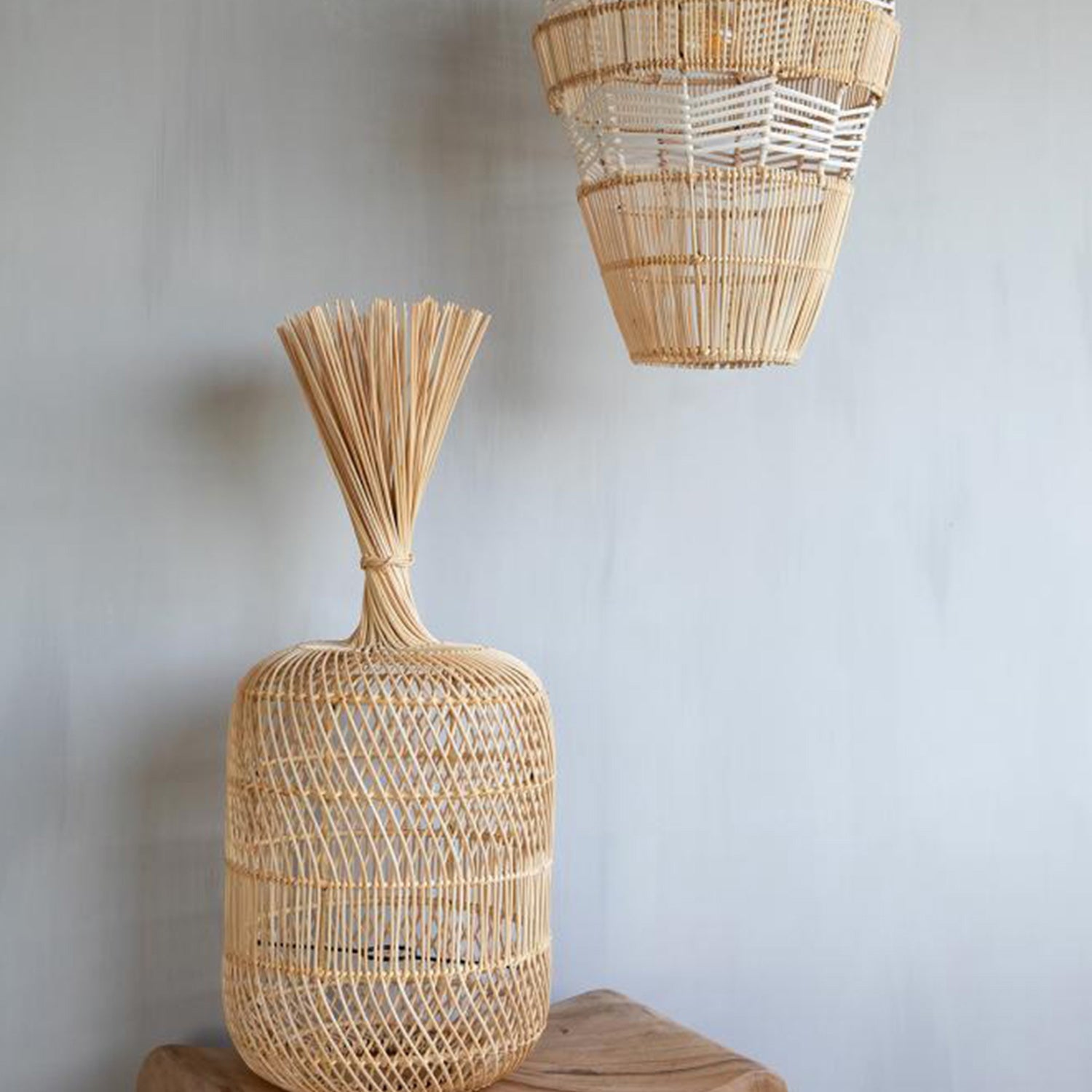 Geweven rotan lampenkap en vaas met speelse patronen, geplaatst tegen een lichtgrijze muur.