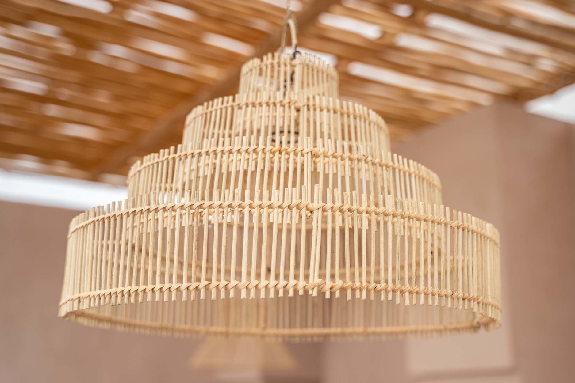 Bamboe hanglamp met een rustieke uitstraling hangt aan een houten plafond in een warme en serene ruimte.
