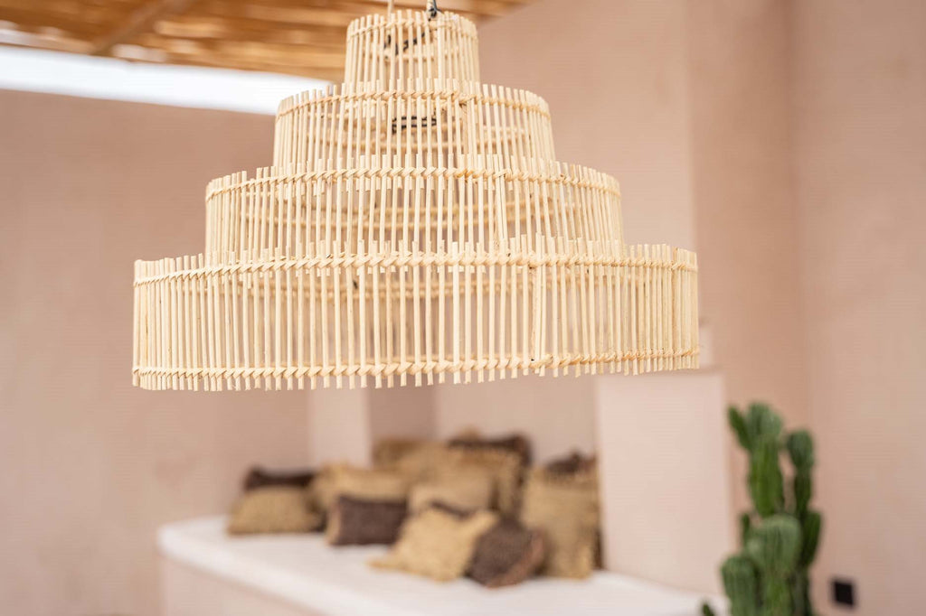 Houten hanglamp met geometrisch ontwerp in rustieke kamer; beige muren, zachte kussens, groene plant.