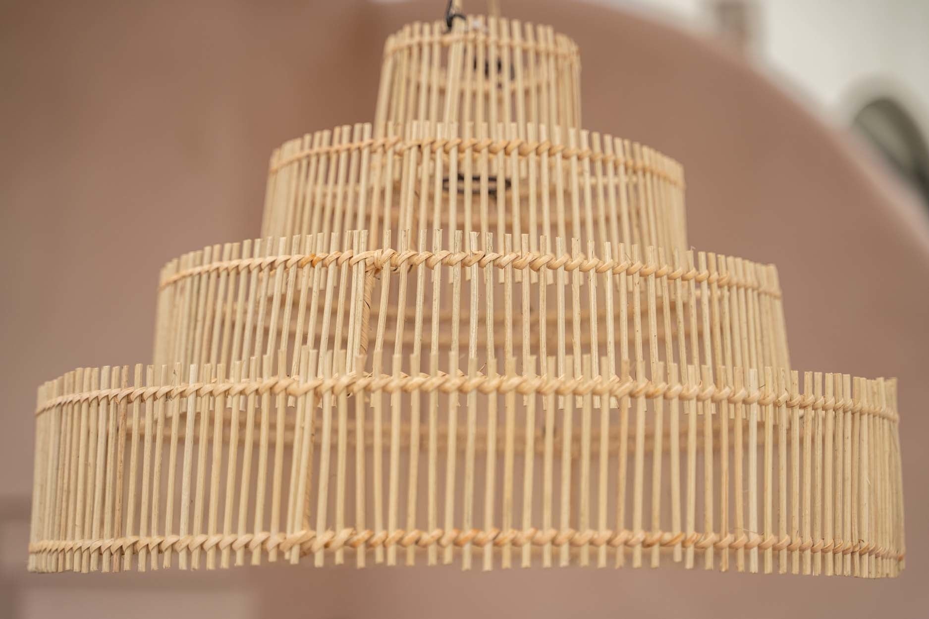 Houten hanglamp met meerdere lagen in een natuurlijke kleur. Geometrisch ontwerp tegen een beige achtergrond.