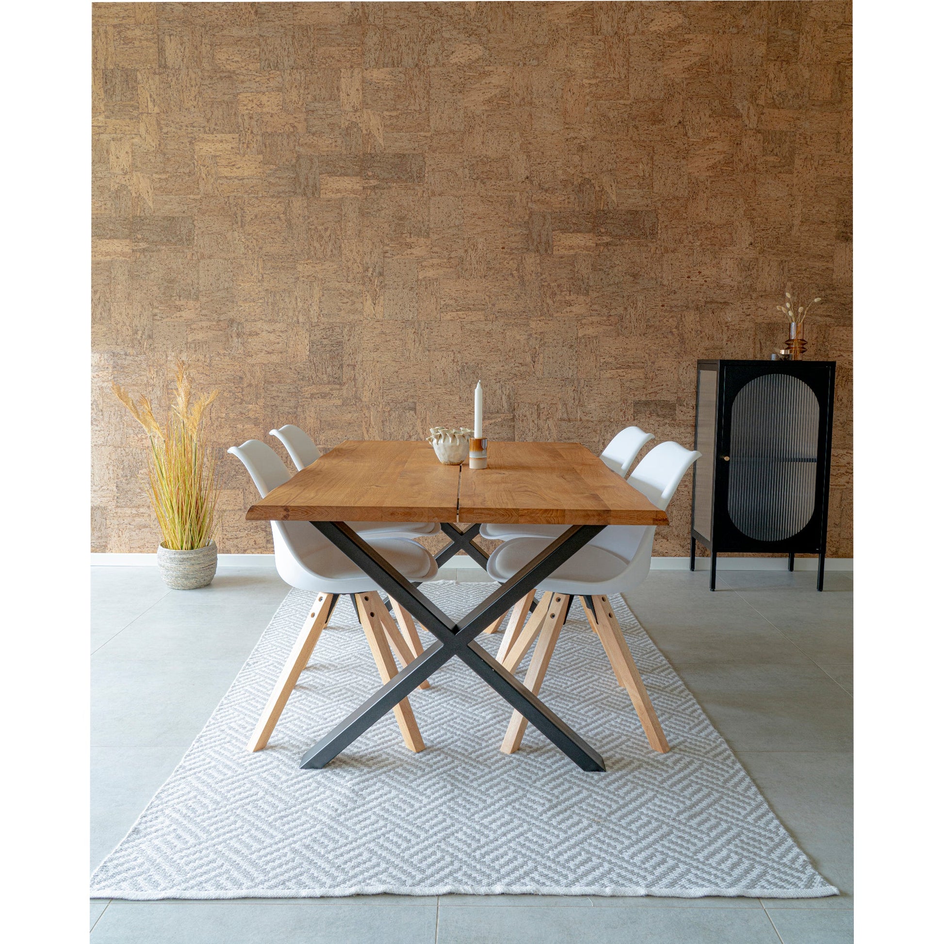 Moderne eetkamer met houten tafel, zes witte stoelen, kurkwand, zwart kastje en een vaas met gedroogd gras.