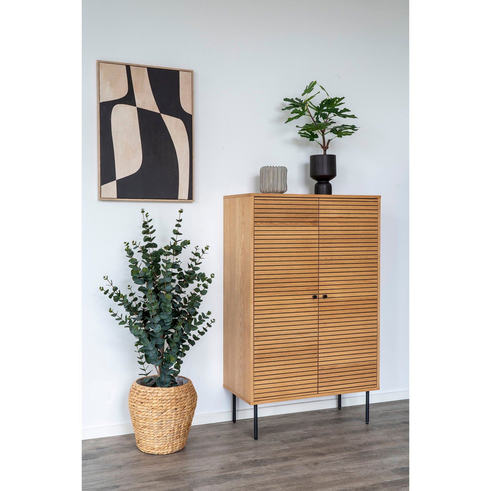 Scandinavische styling met lichtgrijze keramische bloempot Ø15 cm met geribbeld, gespikkeld oppervlak op eiken kast naast zwarte plantenpot