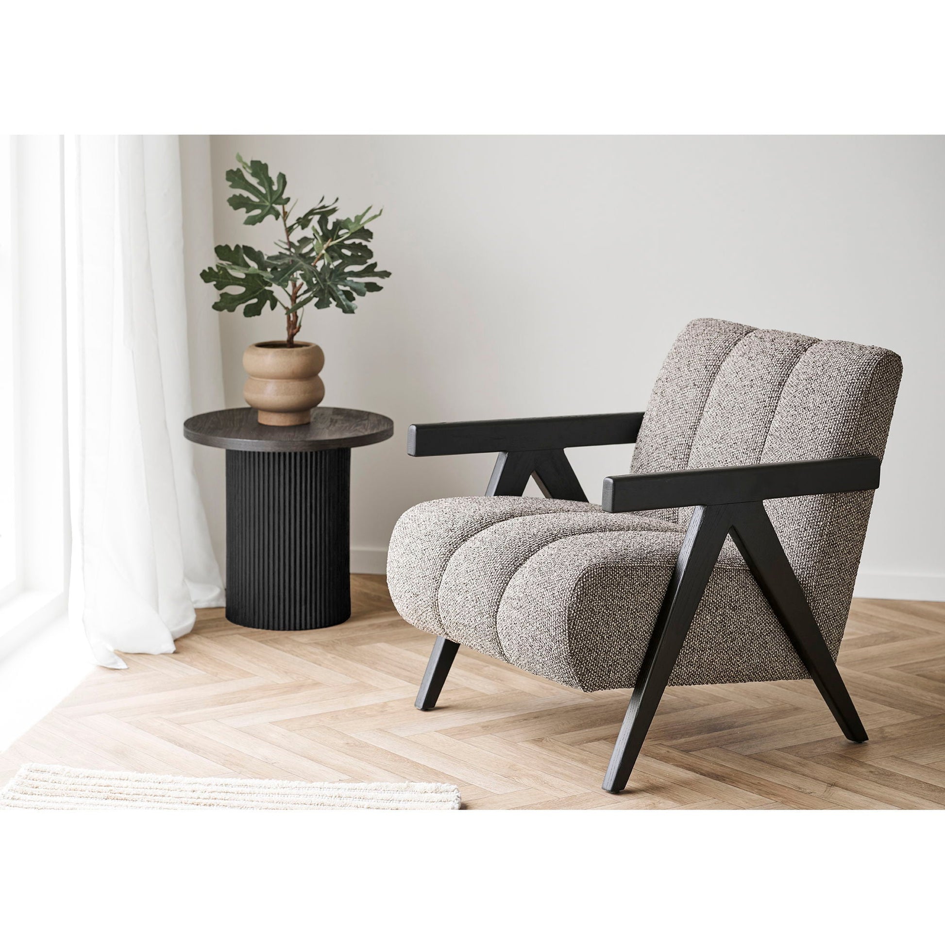 Sfeervolle zithoek met House Nordic Boavista bijzettafel naast bouclé fauteuil voor modern Scandinavisch accent.