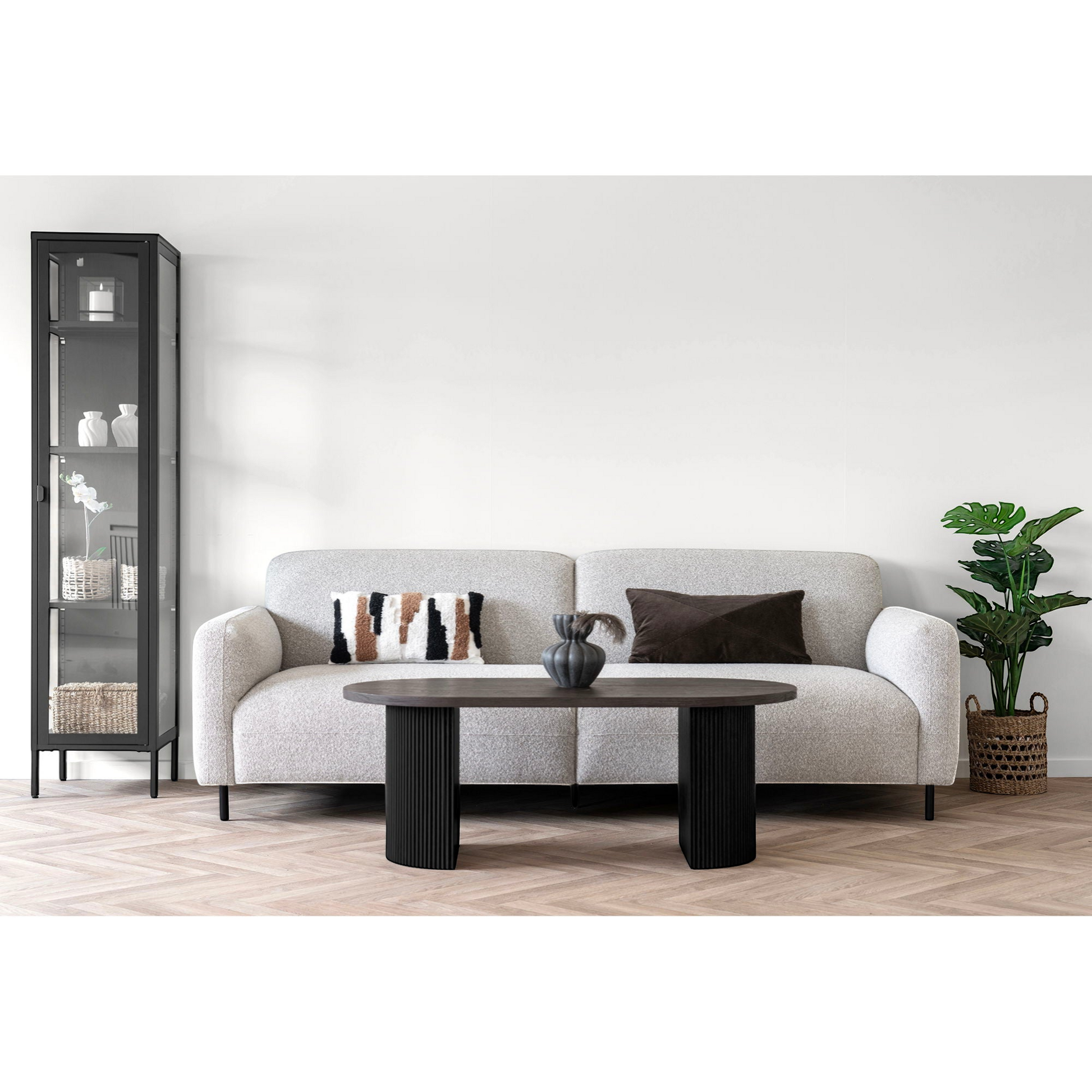 Boavista salontafel in lichte Scandinavische woonkamer met gebogen crème bank, glazen vitrinekast en rieten mand voor warme sfeer