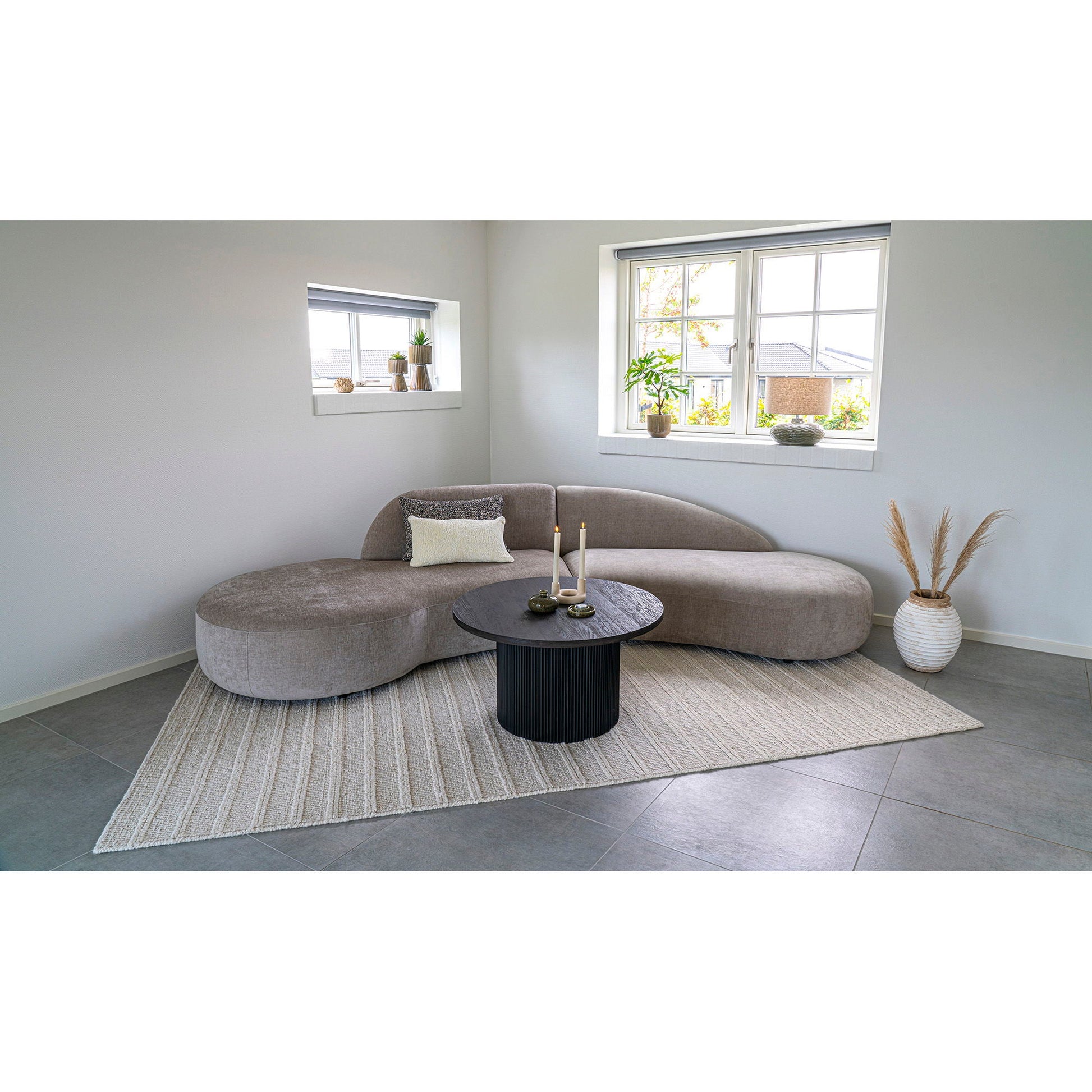 Cosy zithoek met House Nordic Boavista salontafel naast crèmekleurige fauteuil op beige vloerkleed en grijze tegelvloer