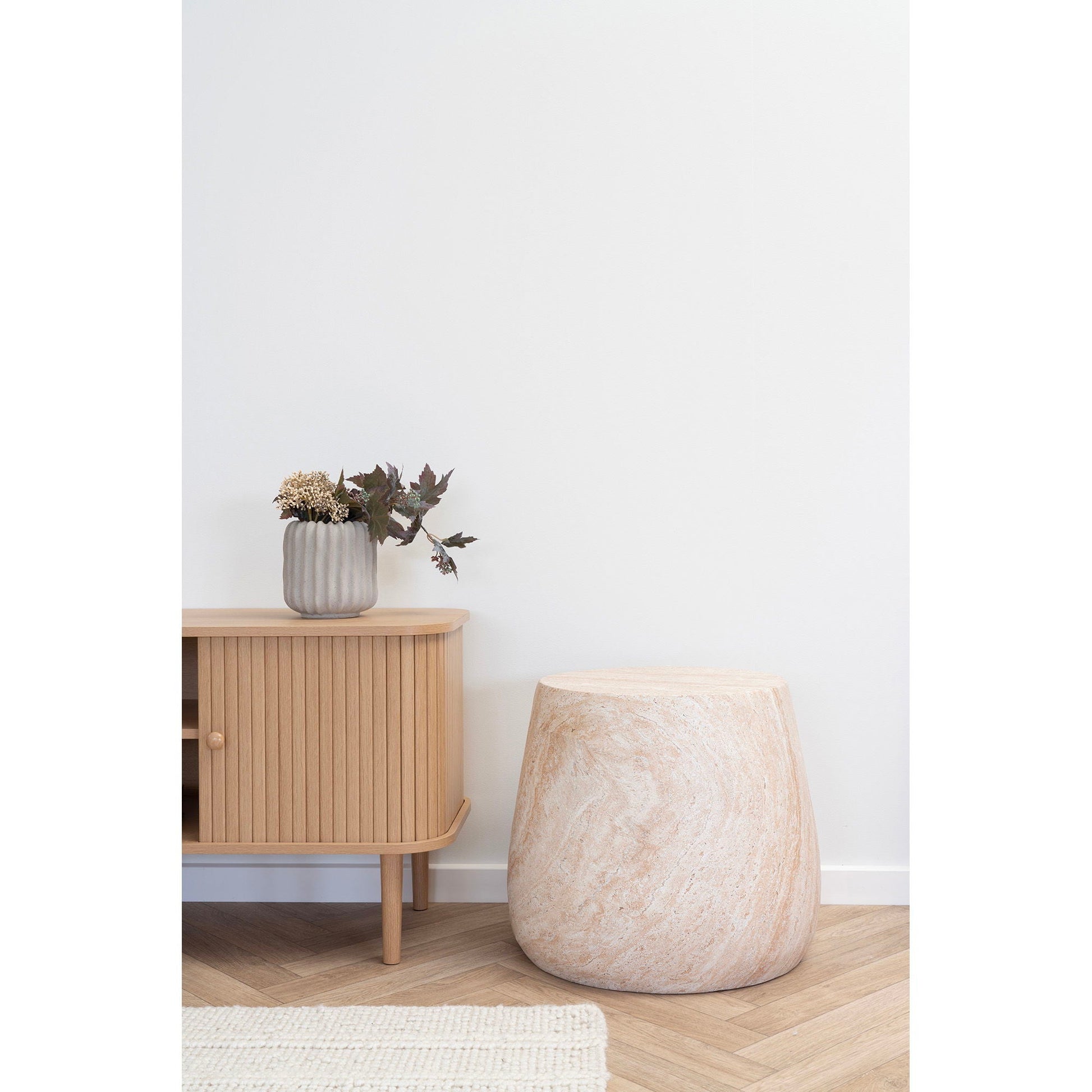 Minimalistische woonstijl met Bonn bijzettafel van House Nordic in naturel fiberclay naast eiken dressoir, visgraatvloer en witte wand