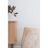 Subtiel interieurdetail met Bonn bijzettafel van House Nordic in naturel fiberclay naast eiken dressoir en ribbelvaas met takken