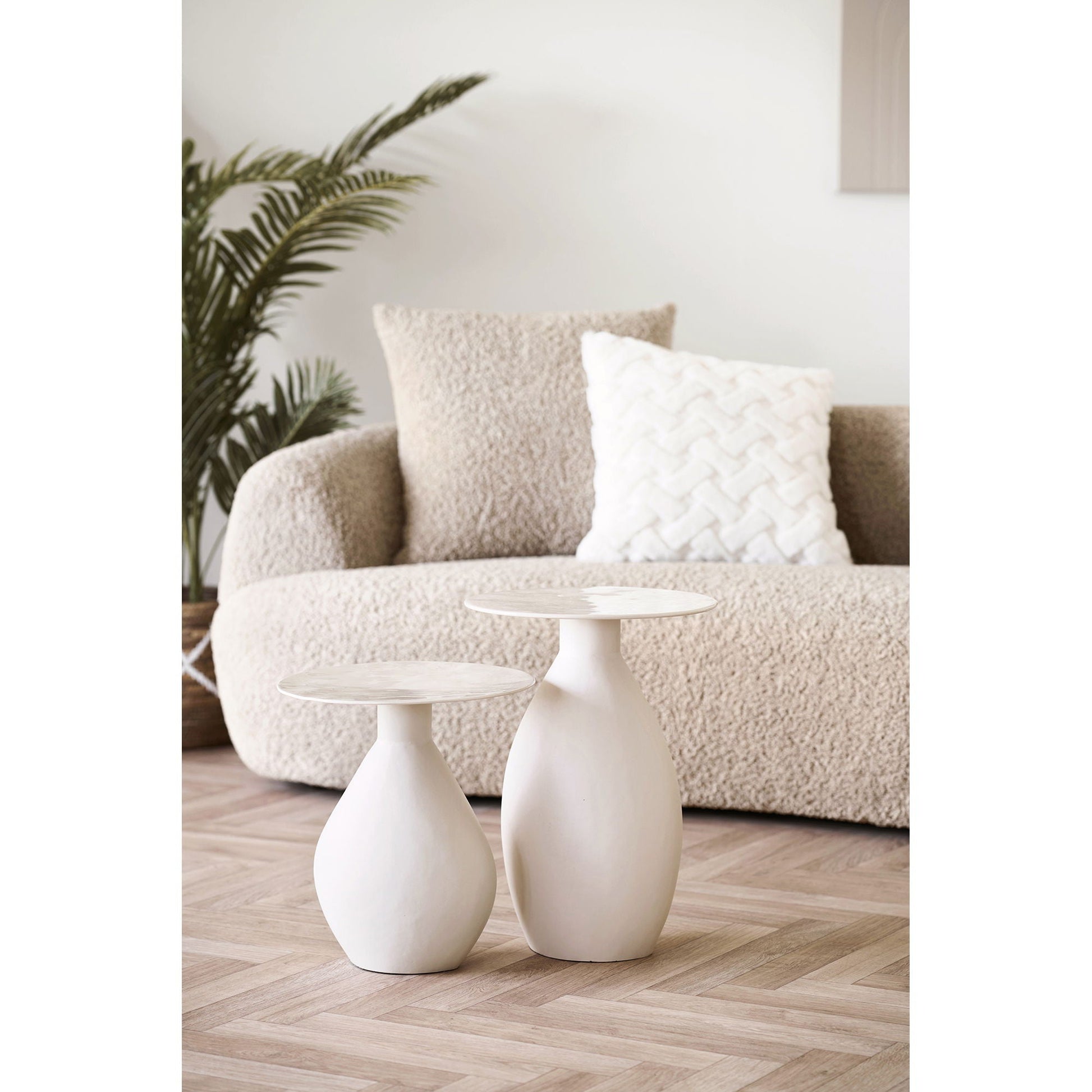 Styling met twee Calais bijzettafels van House Nordic in gebroken wit metaal (Ø36x50 & Ø36x40 cm) naast een boucle bank
