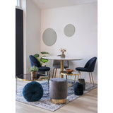 Stijlvolle minimalistische eetkamer met ronde tafel, gouden accenten, blauwe stoelen, en twee ronde spiegels.