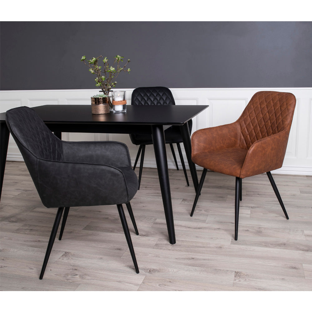 Moderne eetkamer met zwart tafelblad, grijze en leren bruine stoelen, op lichte houten vloer.