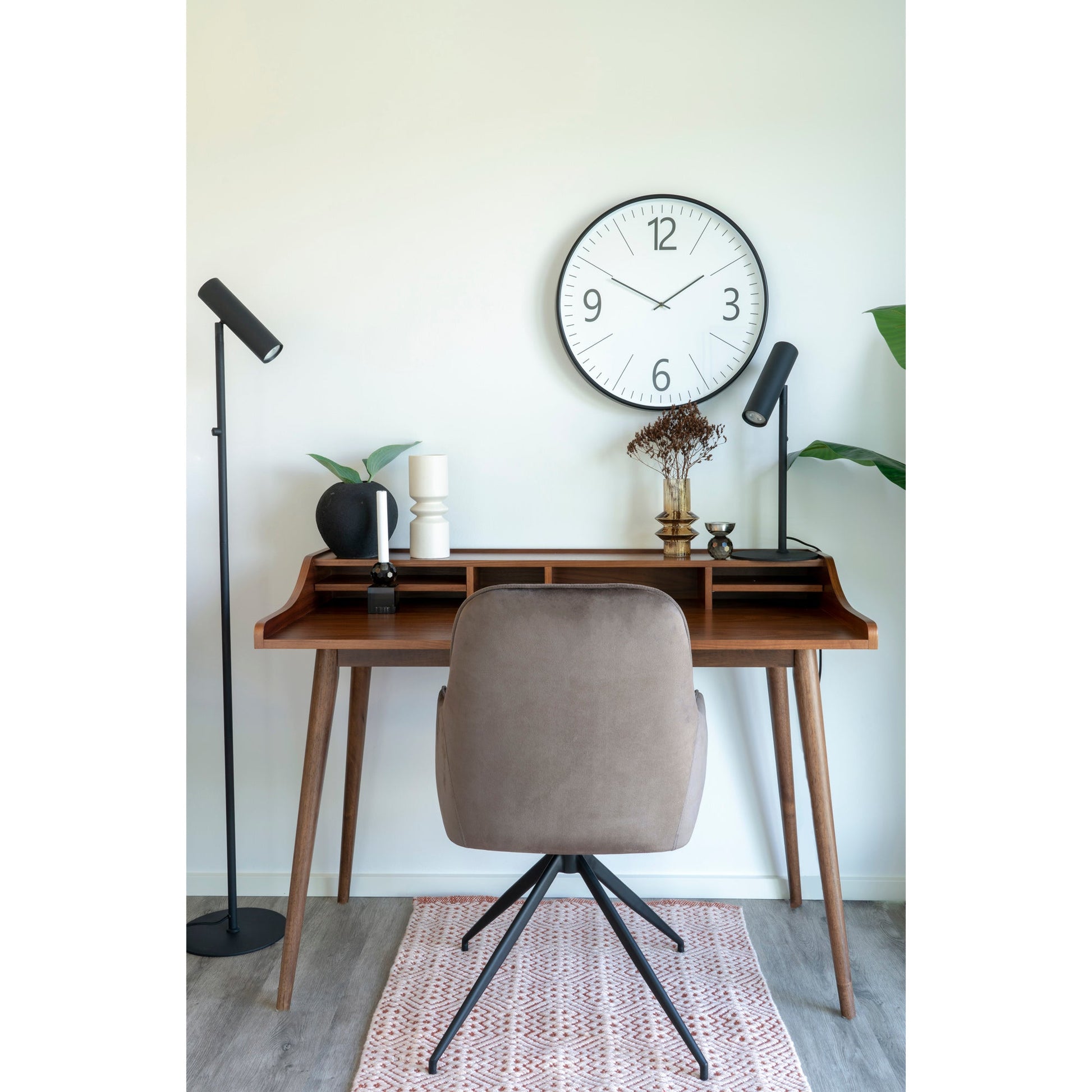 Stijlvolle werkplek met houten bureau, moderne lampen, decoratieve objecten en grote wandklok.