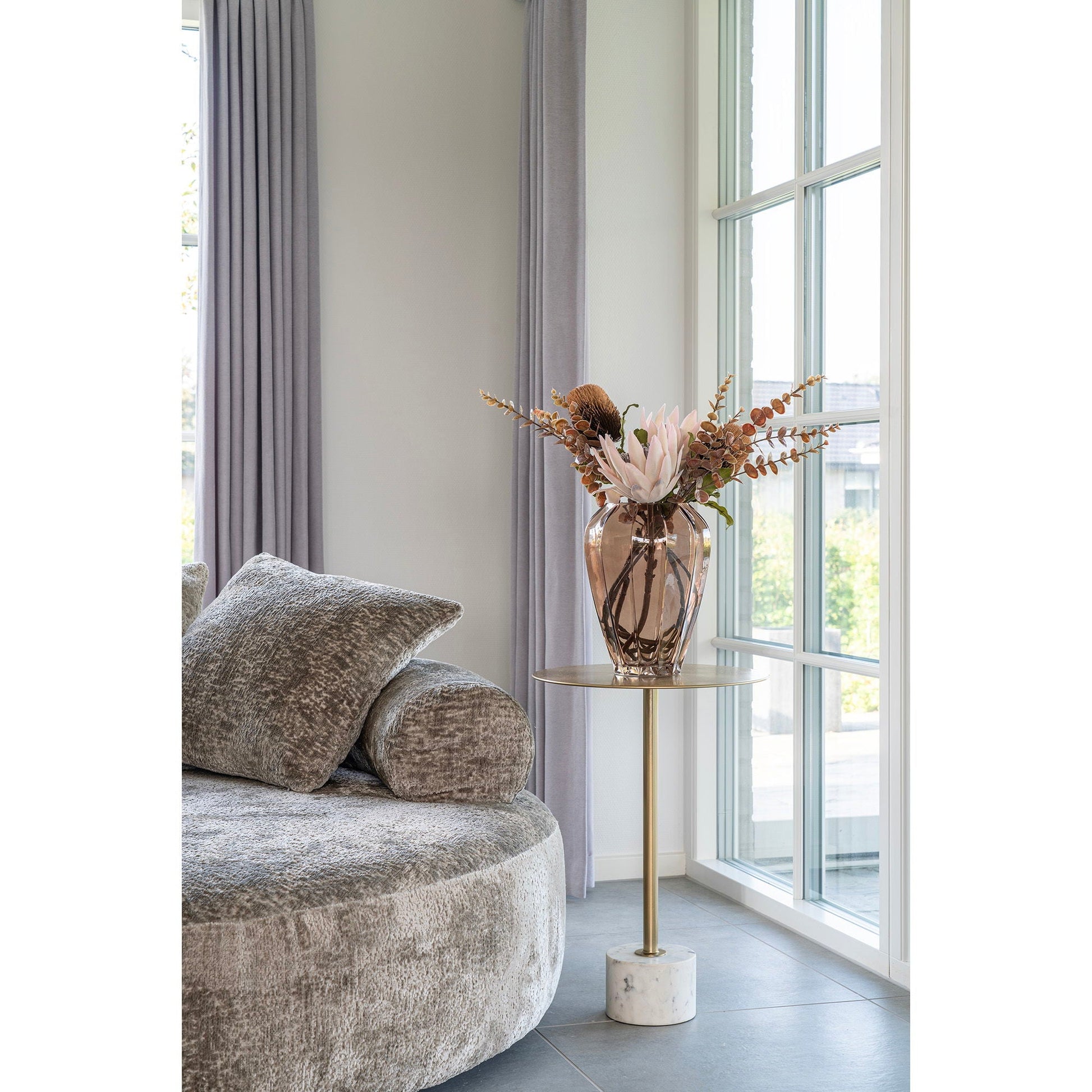 Moderne loungehoek met het House Nordic Lecco bijzettafeltje in messing en wit marmer naast ronde bank