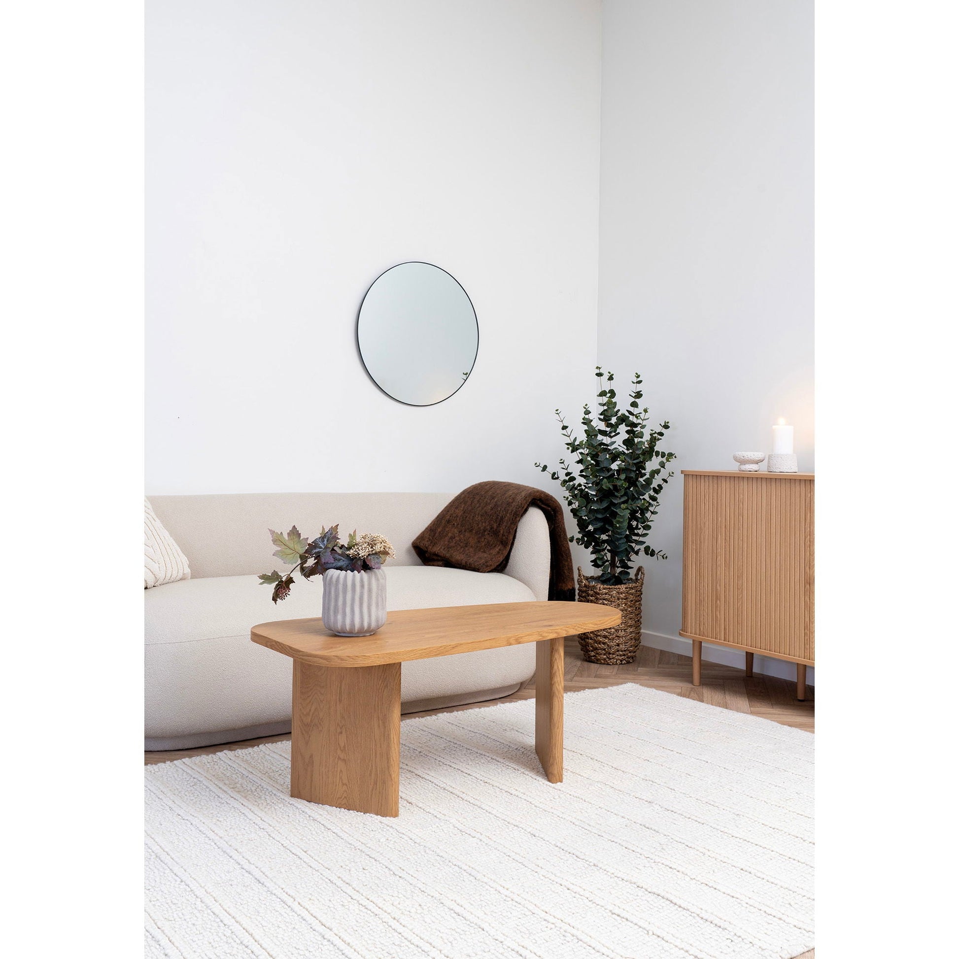Scandinavische woonkamer met Melo salontafel van House Nordic in naturel MDF, wit vloerkleed, plantenmand en poef