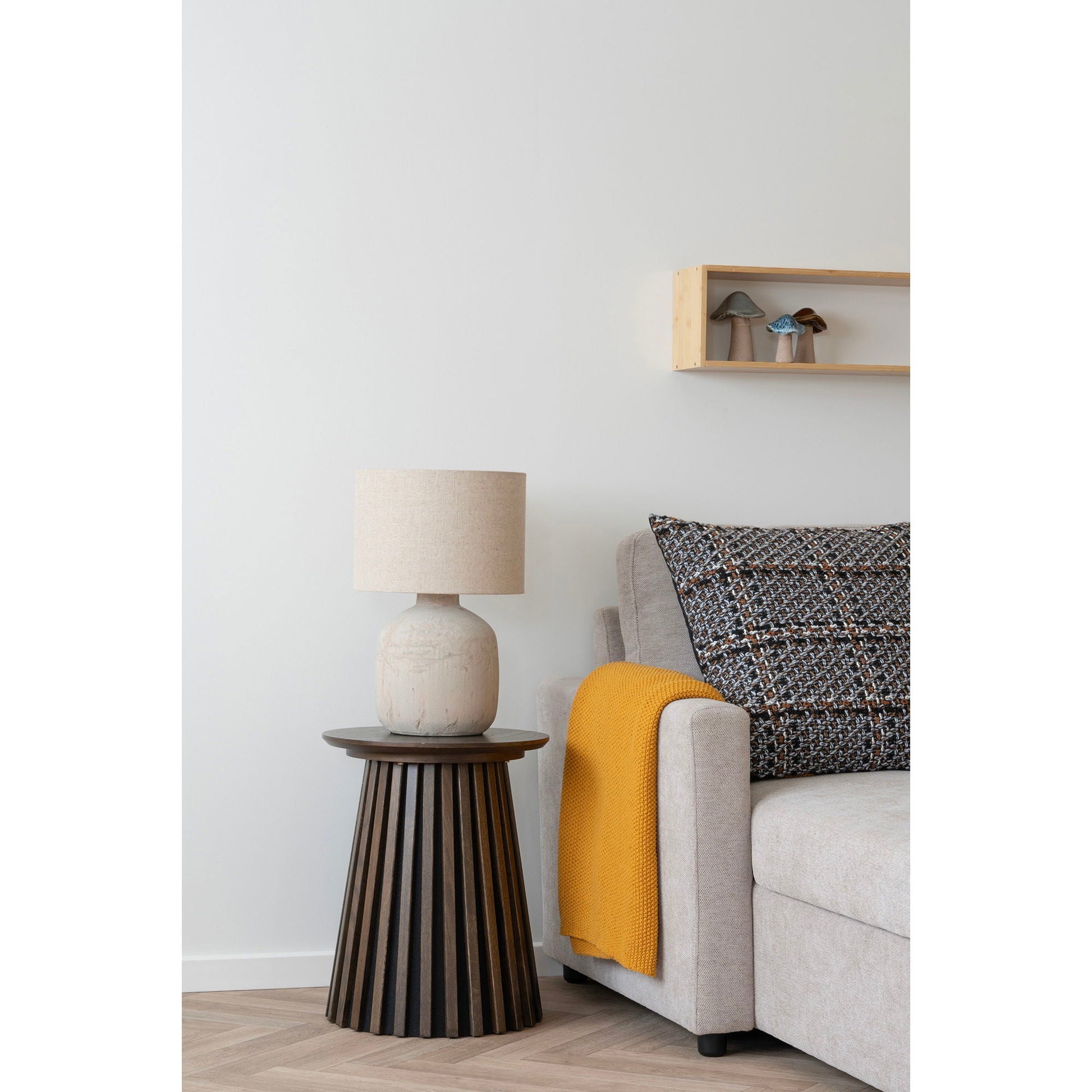 Gezellige zithoek met House Nordic Osaka bijzettafel naast lichtgrijze bank, beige tafellamp, okergeel plaid en keramische accessoires