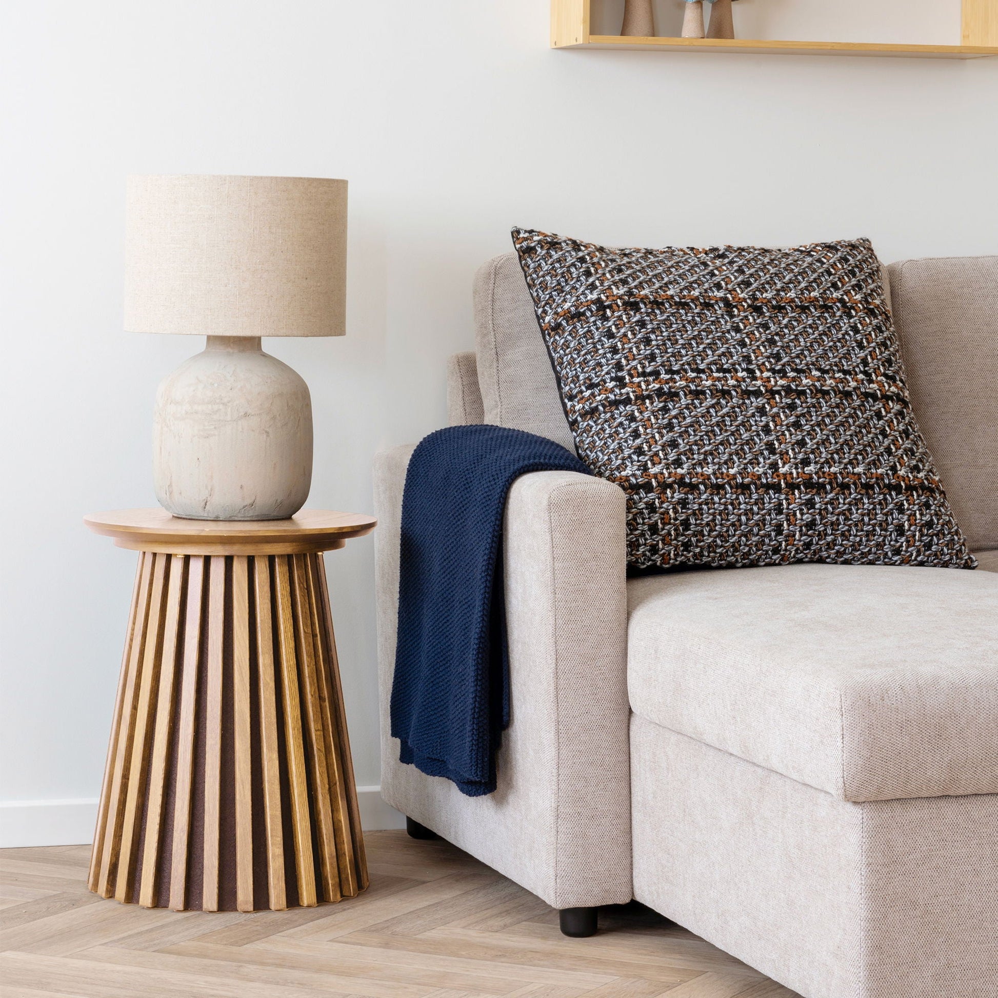 House Nordic Osaka bijzettafel van eikenfineer naast beige bank met gebreid donkergrijs kussen en keramische tafellamp