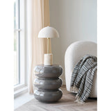 Scandinavische styling met Rosolina bijzettafel van bruin glasvezel als lampenstandaard naast off-white bouclé fauteuil