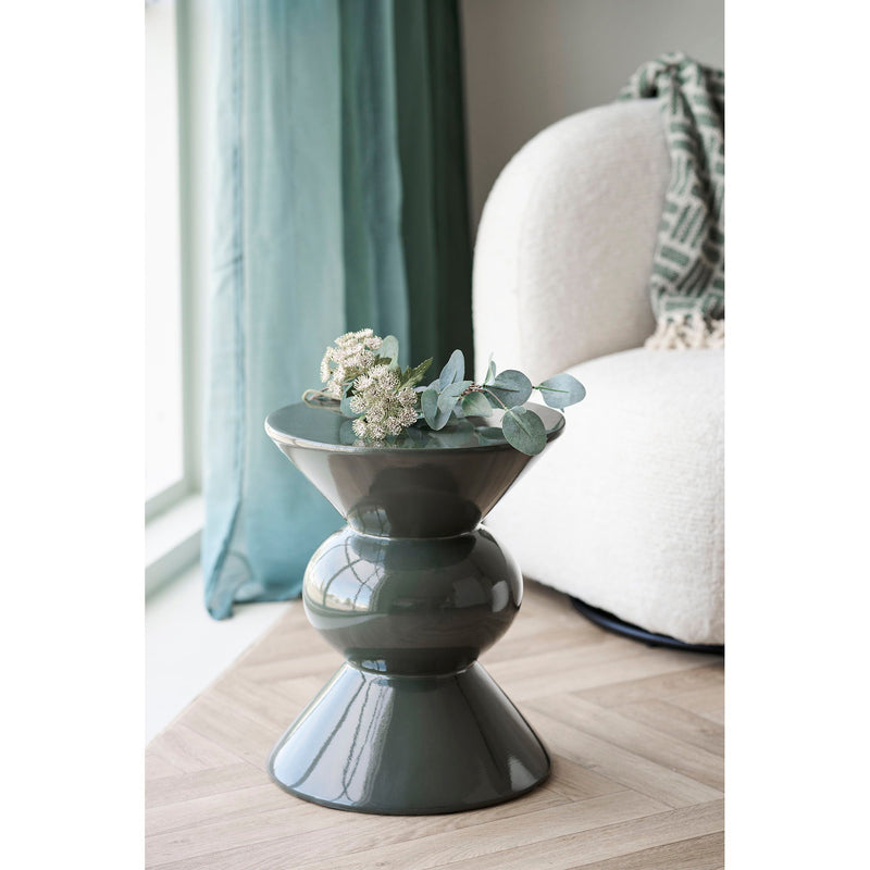 House Nordic Rosolina bijzettafel gestyled met witte bloesem en eucalyptus naast een creme bouclé fauteuil en groen gordijn
