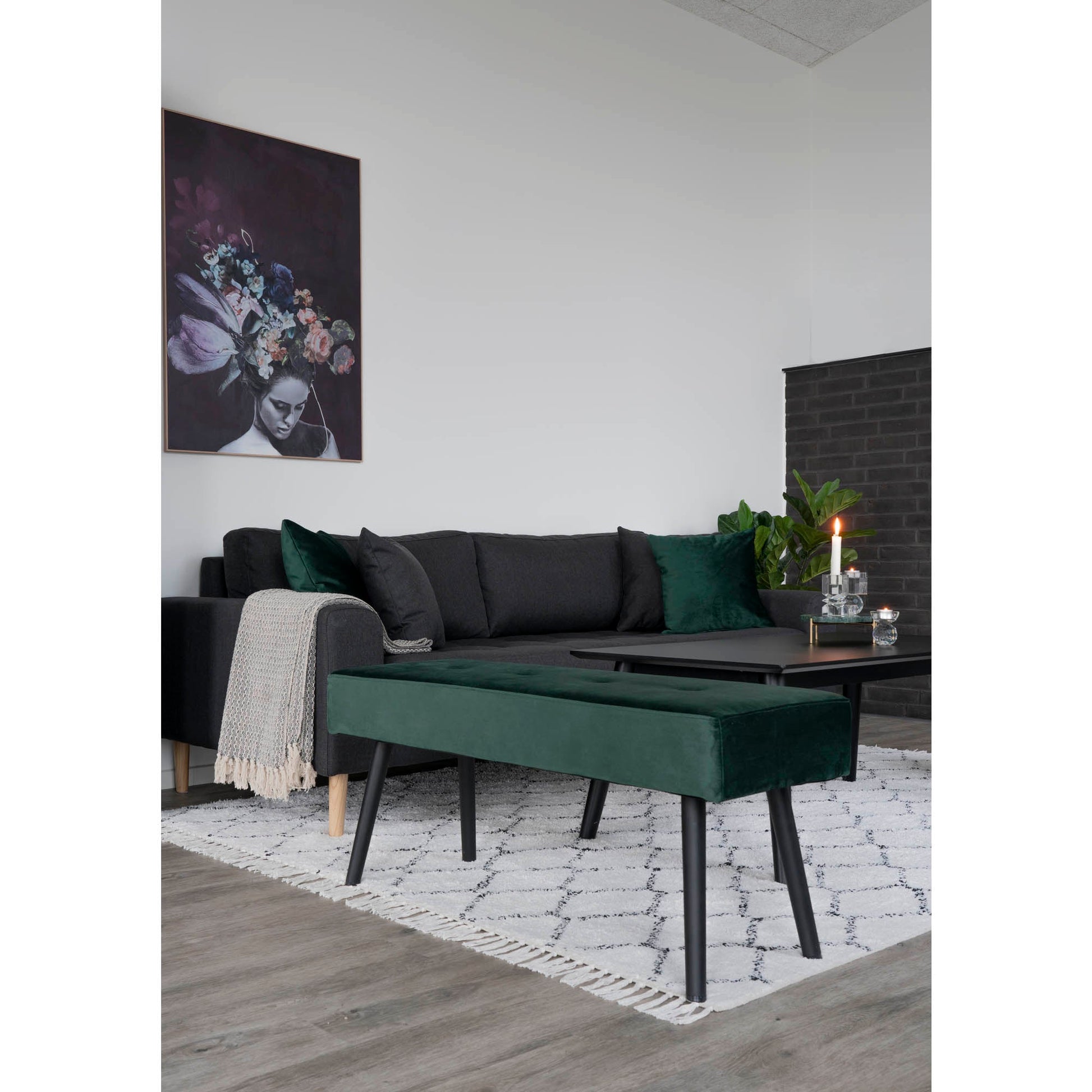 Donkere hoekbank met groene kussens, een groene fluwelen bank, brandende kaars op tafel, bloemenschilderij.