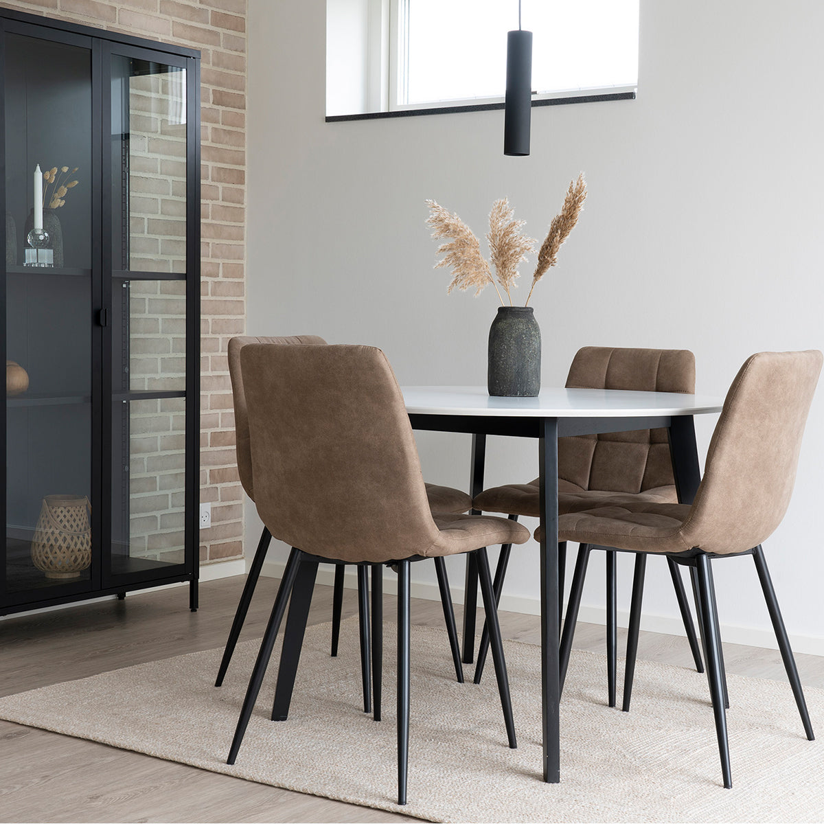 Eettafelset met vier bruine stoelen rond witte tafel, decoratieve vaas op tafel naast zwarte vitrinekast.