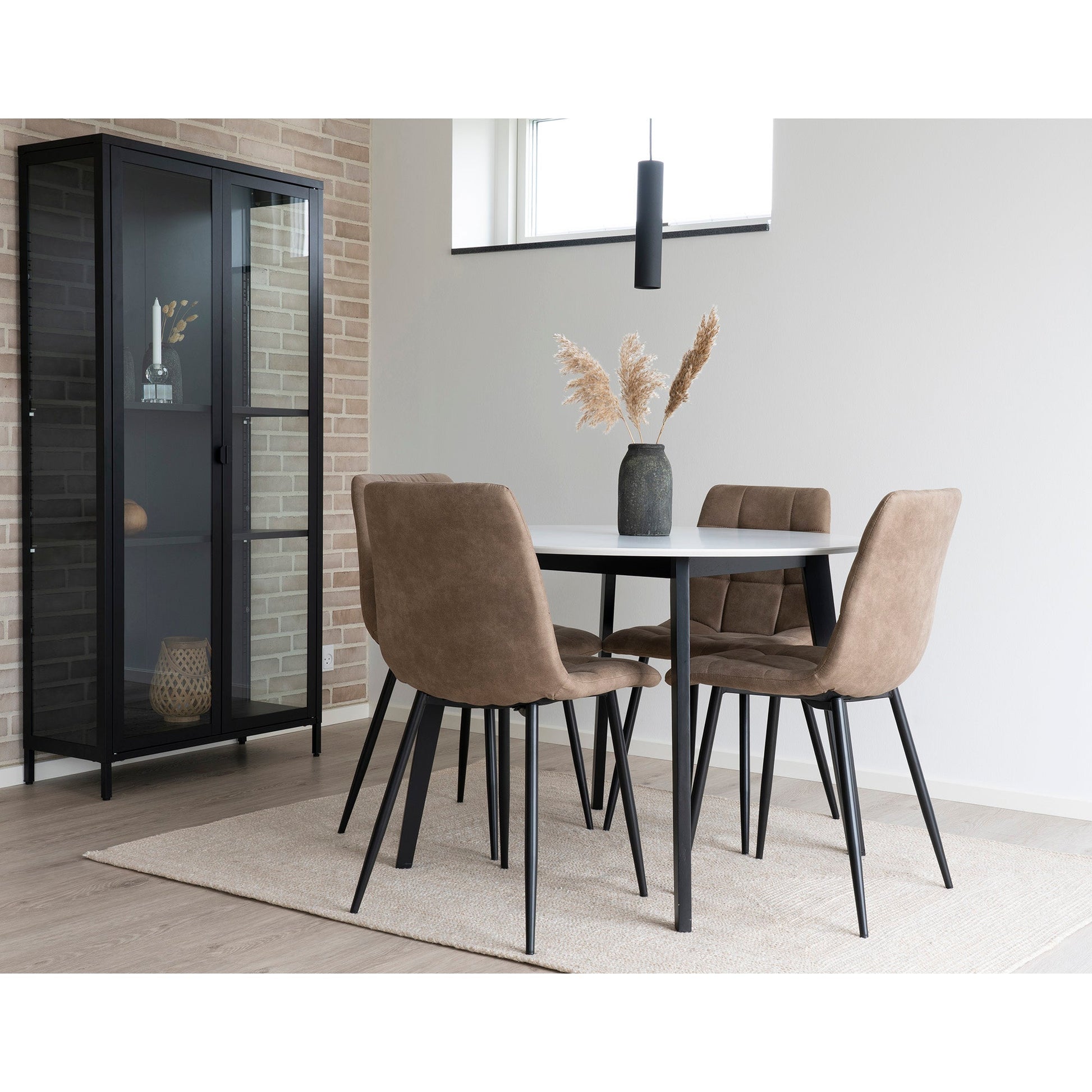 Moderne eetkamer met vier bruine stoelen, wit tafelblad, vaas met gedroogd pampasgras en glazen kast.