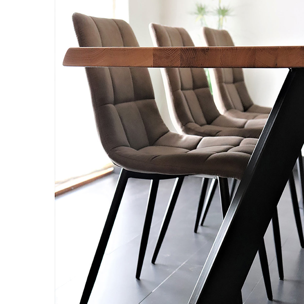 Stijlvolle bruine gestoffeerde eetkamerstoelen met een houten tafelblad op zwarte poten in een moderne ruimte.
