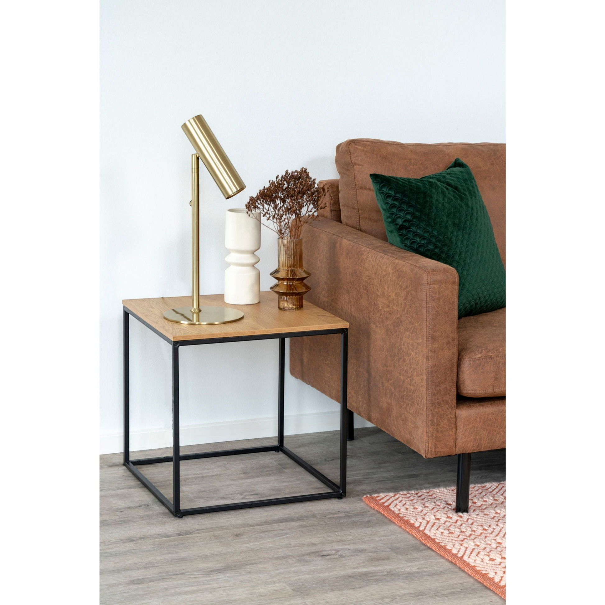 Vita bijzettafel van House Nordic naast blauwe fluwelen bank als sofazijtafel met tafellamp en vaas op eikenlook blad.