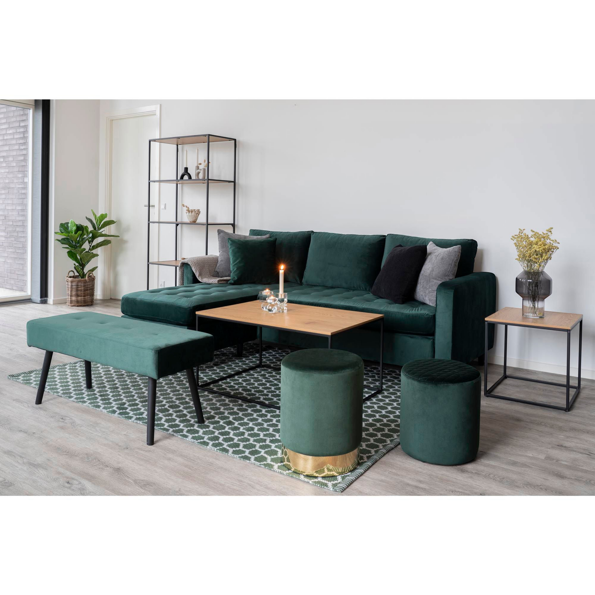 Sfeervol beeld van Vita bijzettafel van House Nordic naast twee groene velvet poefs op een geometrisch tapijt.