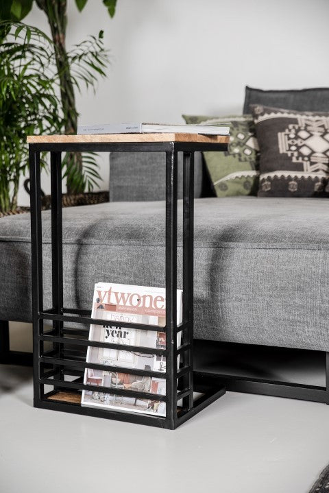 Industrieel bijzettafeltje met houten blad, zwart frame, tijdschriftenopslag, grijze bank, groene kussen.