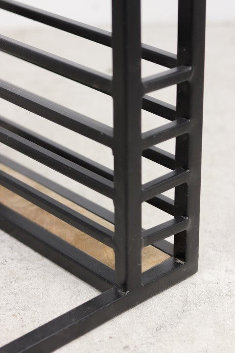 Zwarte metalen staven in een modern, hoekig ontwerp op een betonnen oppervlak met houten details.