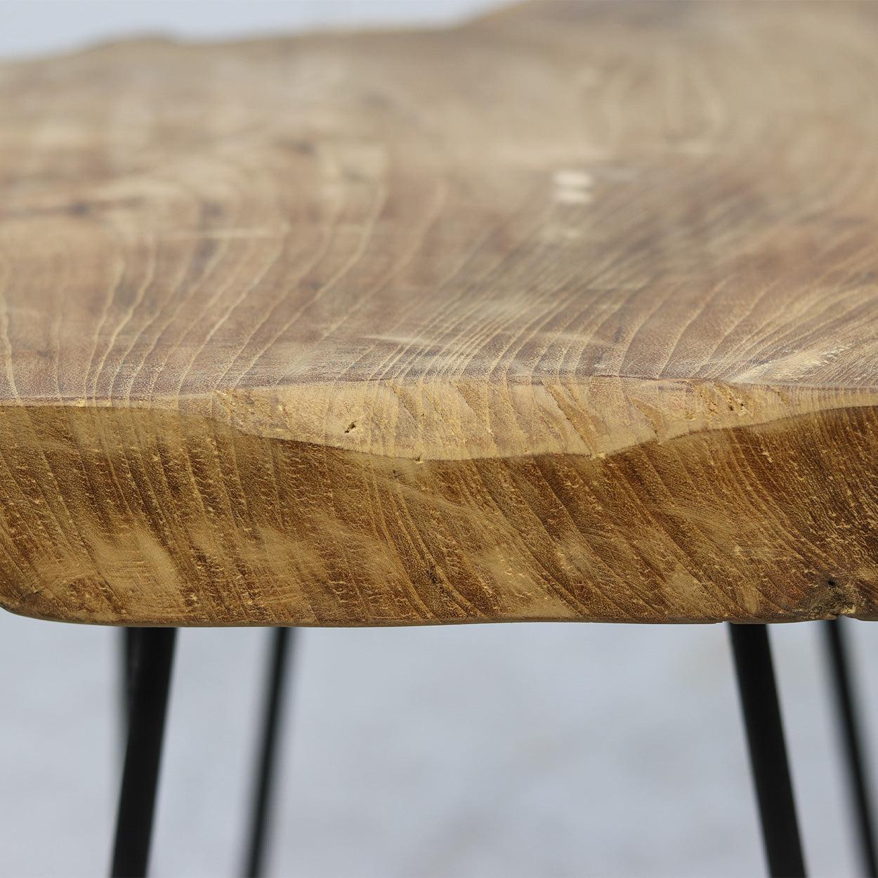 Natuurlijke houten tafelblad met zichtbare nerfstructuur, ondersteund door zwarte metalen poten.