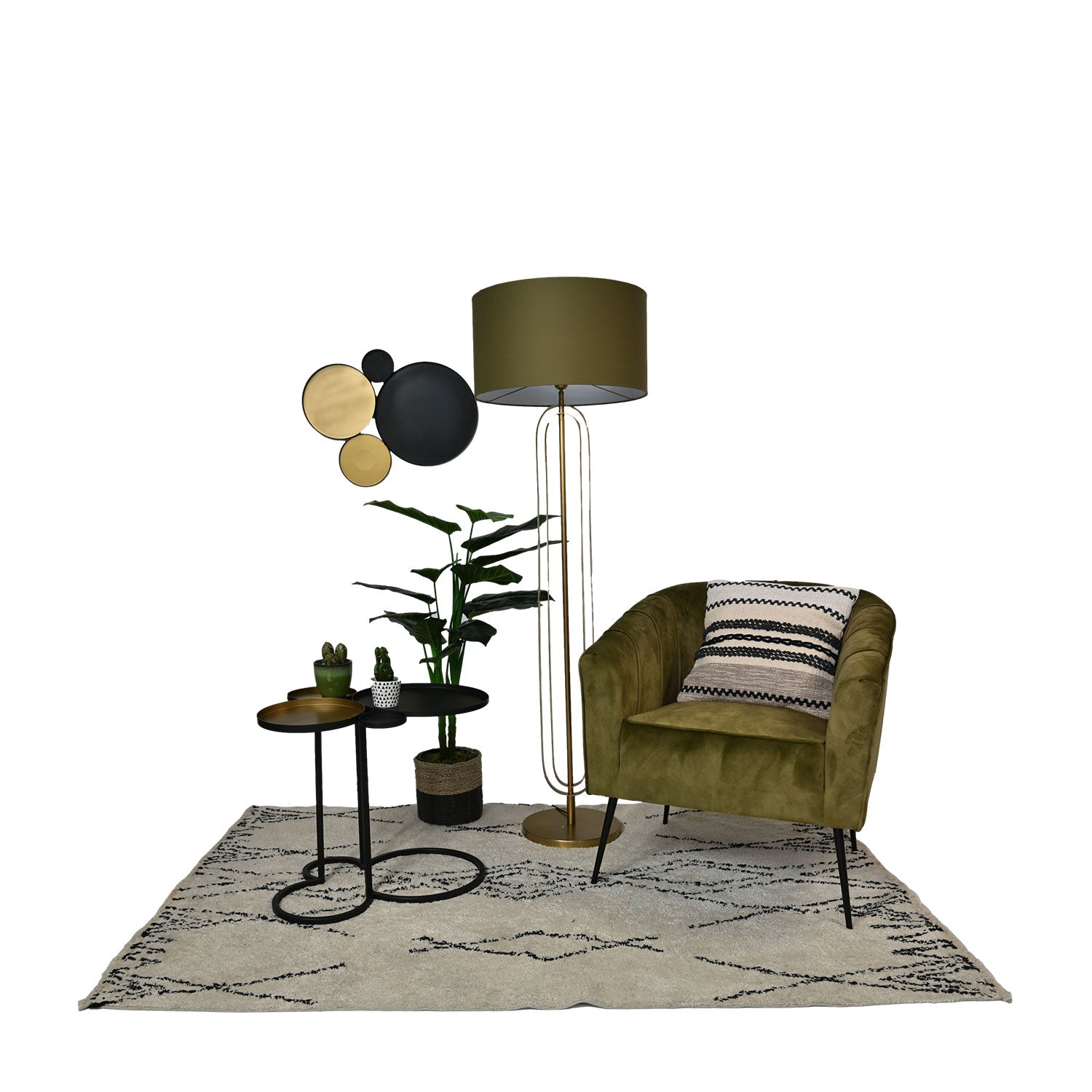 Groene fauteuil met zwart-wit kussen, metalen bijzettafels, vloerlamp, planten en wanddecoratie op vloerkleed.