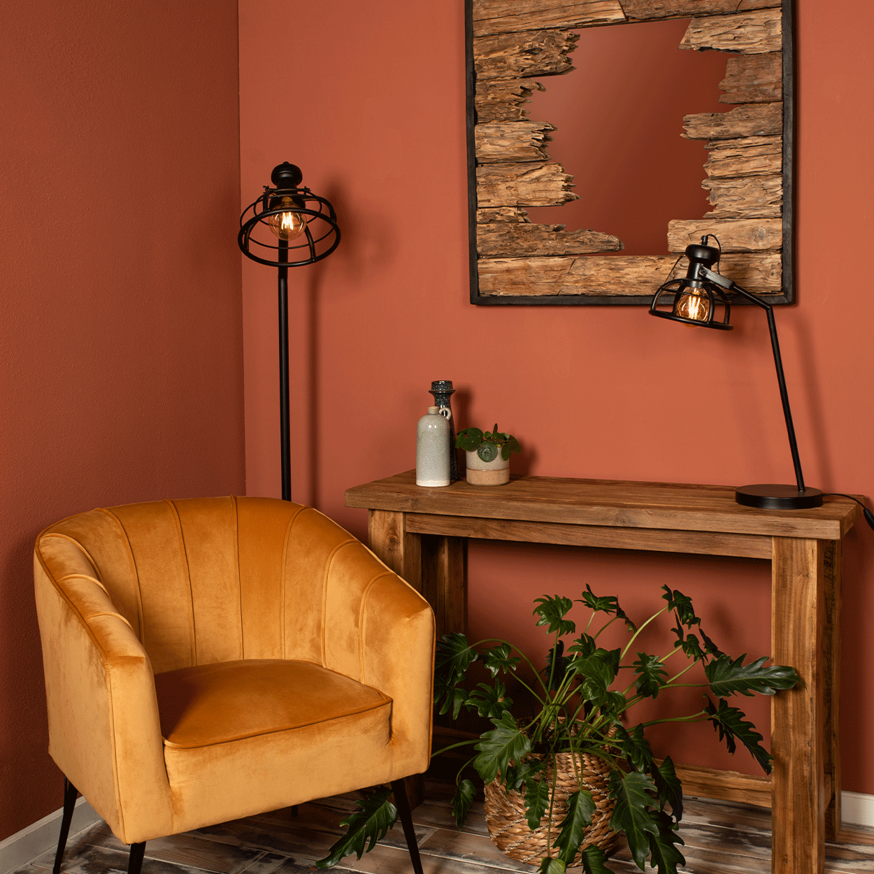 Mosterdgele fauteuil in hoek met houten tafel en spiegel op bakstenen muur, sfeervol verlicht, groene plant.