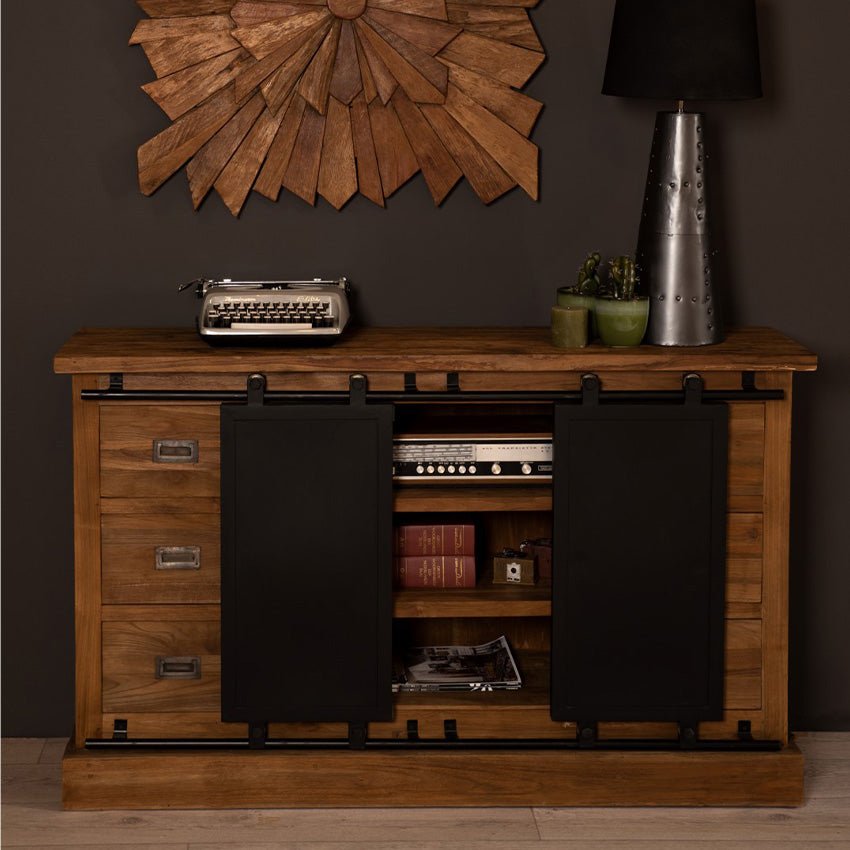 Houten dressoir met typemachine, retro radio en boeken, versierd met metalen lamp en houten wanddecoratie.