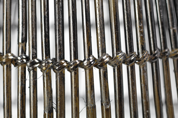 Close-up van verroeste metalen staven gebonden met draden, patroon van verweerd ijzer en textuur.