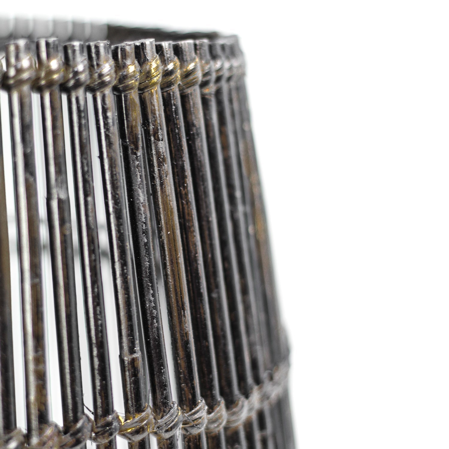 Detail van een zilverkleurige metalen draadlampenkap met slanke, parallelle staafjes en subtiele roestplekken.