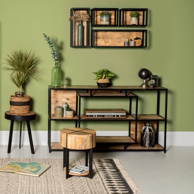 Industrieel ingericht interieur met houten meubels, planten en accessoires tegen een olijfgroene muur.