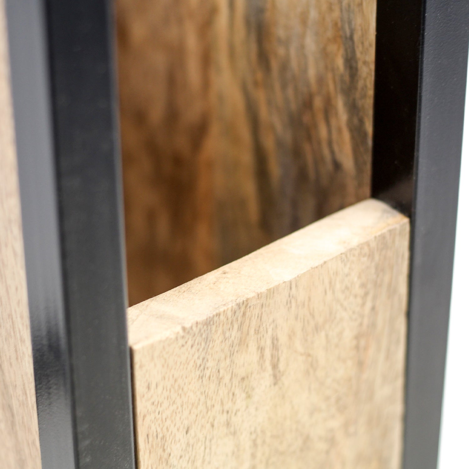 Close-up van een houten plank tussen twee zwarte metalen kaders met een natuurlijke houtnerf.