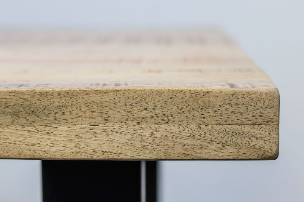Desktop van licht hout met fijne nerfstructuur, tegen een neutrale achtergrond, met zwart metalen onderstel.