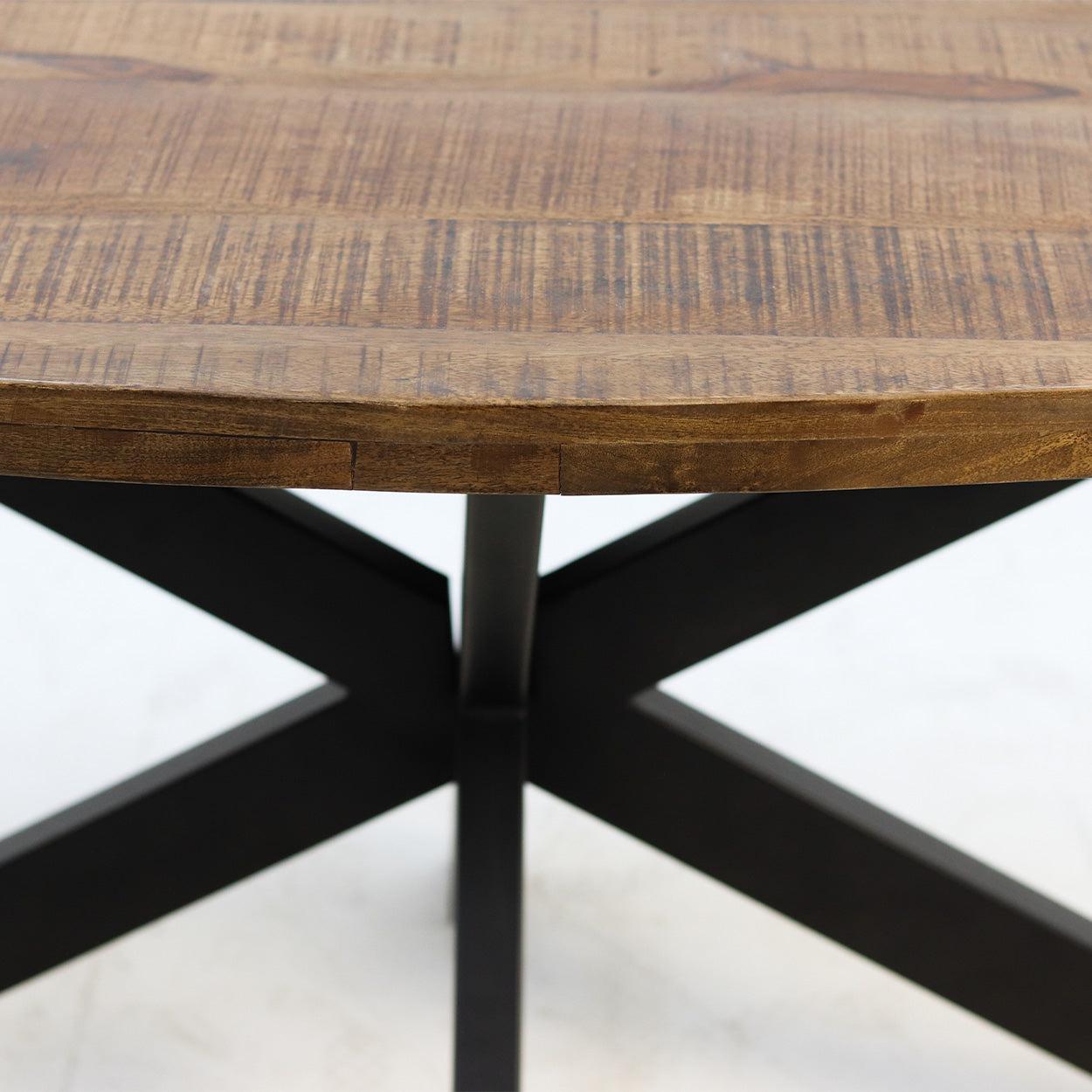 Robuuste houten tafelblad met natuurlijke houttextuur, op zwarte metalen X-vormige poten.