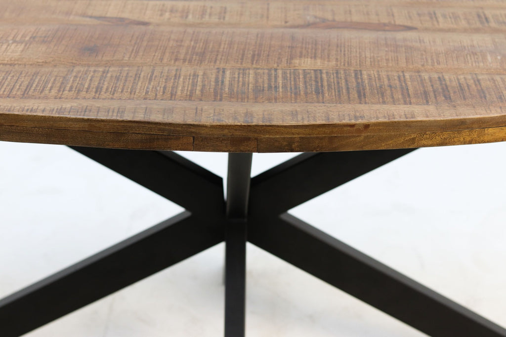 Ronde houten tafel met rustieke uitstraling, stevig zwart metalen onderstel in kruisvorm op witte achtergrond.