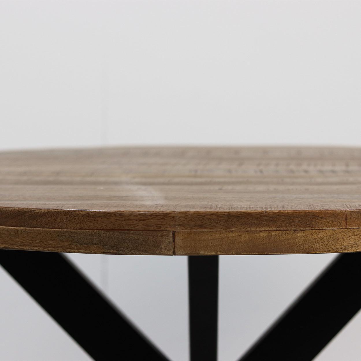 Ronde houten tafel met natuurlijke houtnerf op zwart metalen onderstel tegen witte achtergrond.
