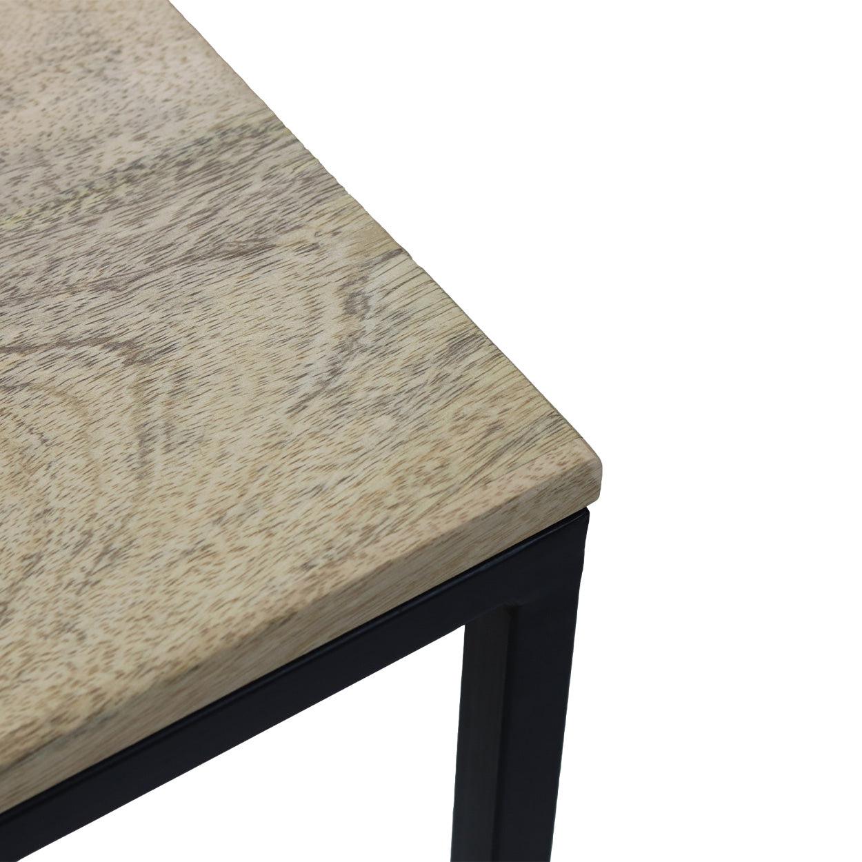 Hoek van een minimalistische tafel met licht houten blad en zwart metalen frame, strak en modern design.