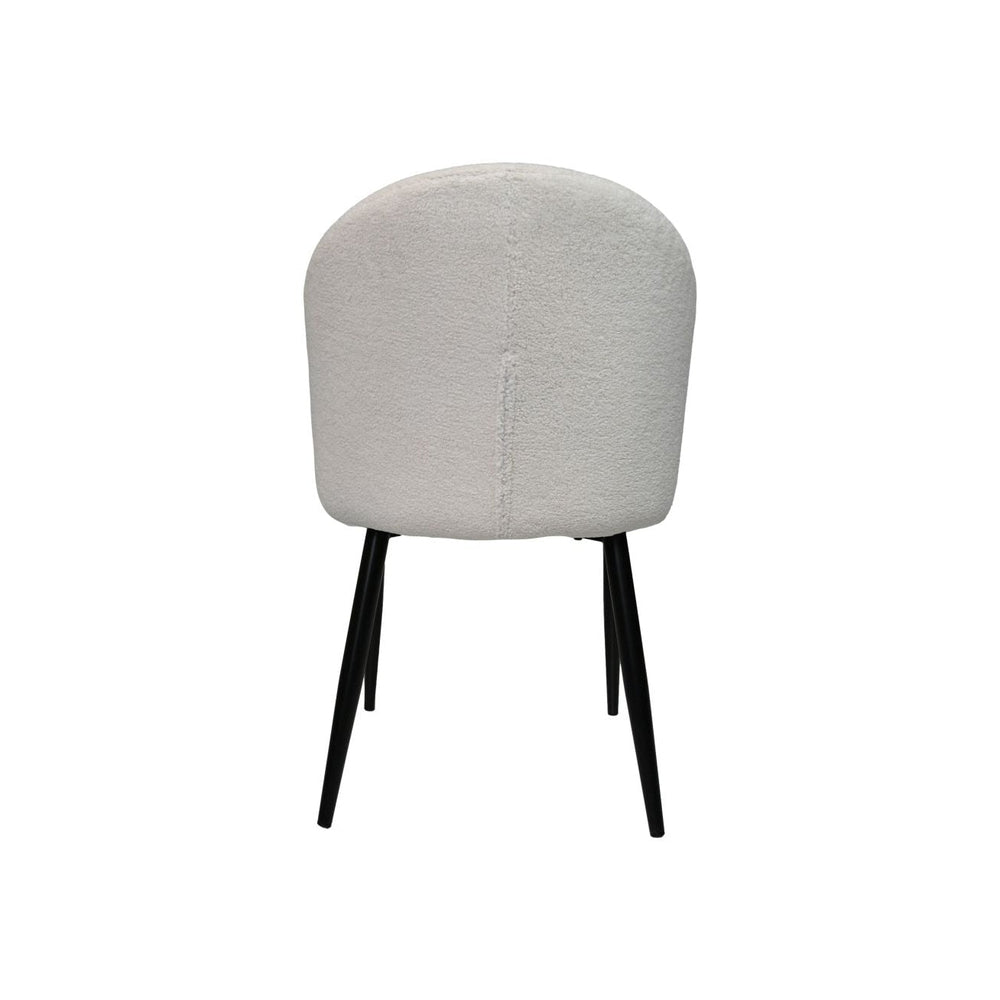 Stijlvolle stoel met zachte, crèmekleurige bekleding en slanke, zwarte metalen poten, minimalistisch design.