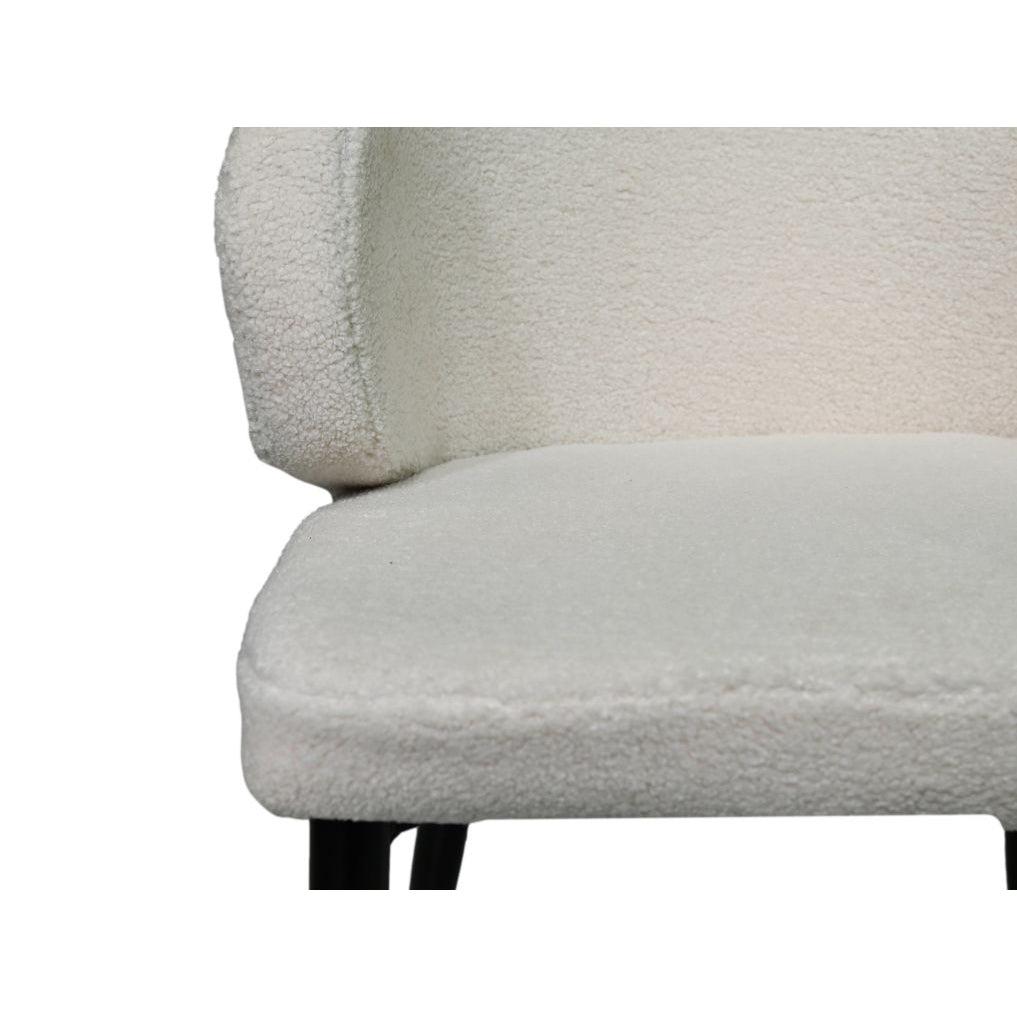 Witte fauteuil met zachte, getextureerde bekleding en donkere houten poten, minimalistisch design.