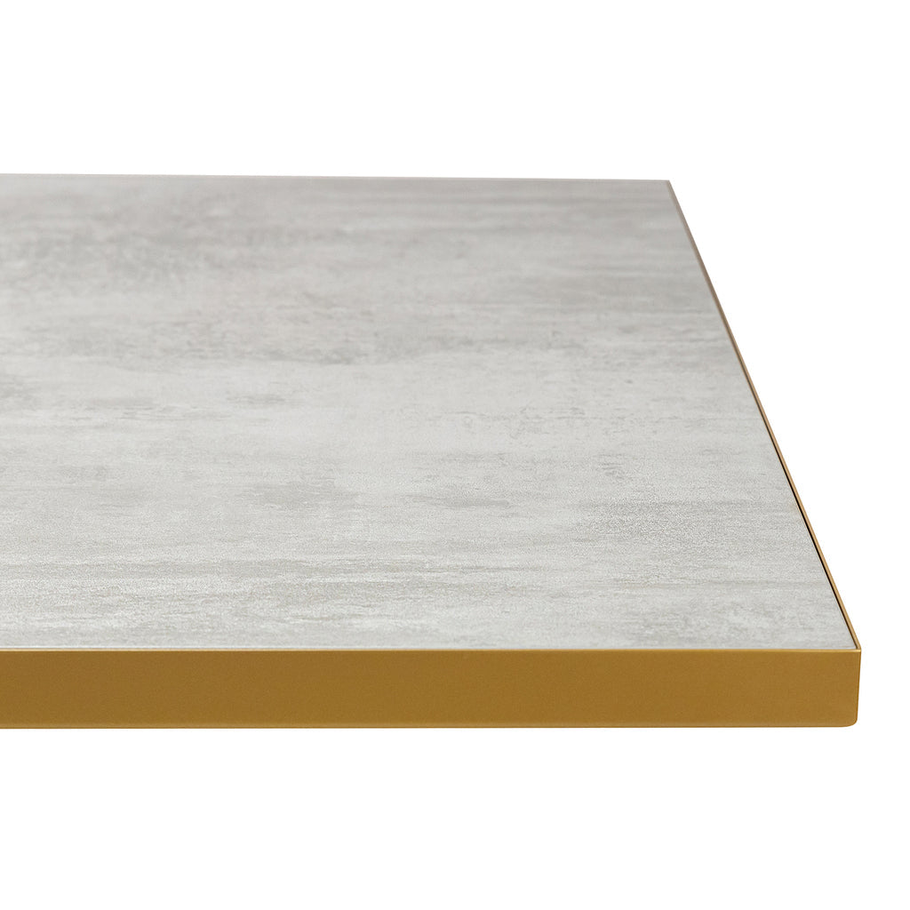 Grijs tafelblad met een marmerachtige textuur en een gouden rand, gezien vanuit een laag perspectief.