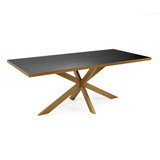 Moderne tafel met een donker houten blad en een goudkleurig metalen kruisvormige pootconstructie.