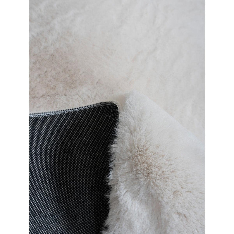 Wit schapenvacht kleed met zachte pluche textuur en donkere achterkant, elegant gedrapeerd.